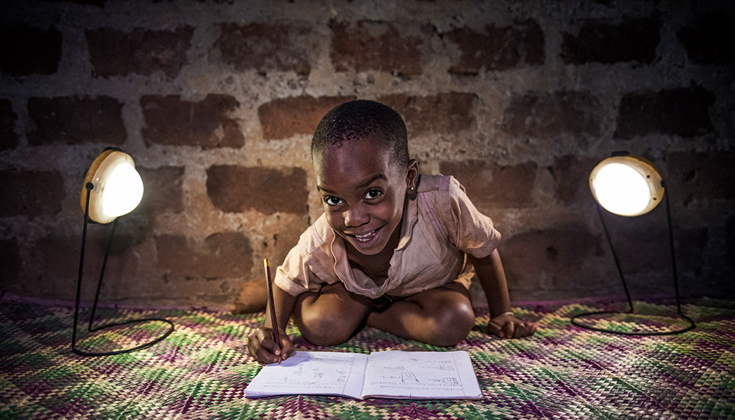 A child does her school work using solar lanterns from BrightLife, FINCA's social enterprise in Uganda.